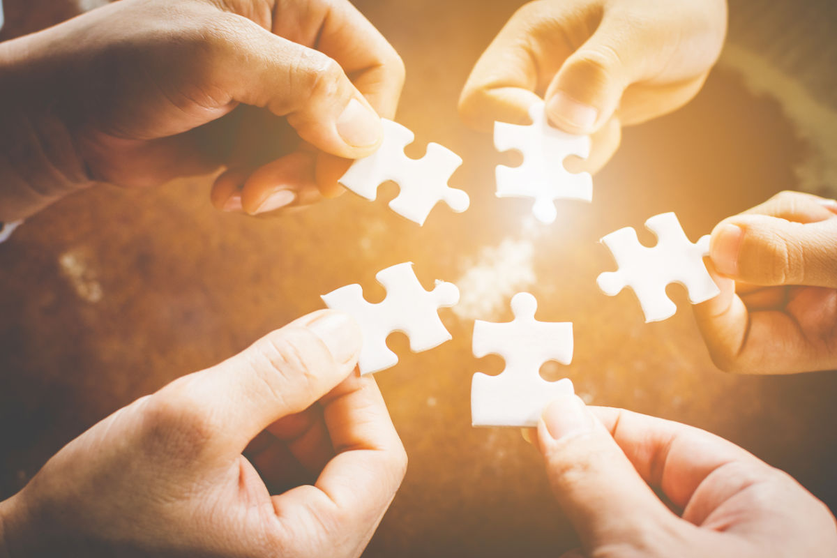 Hand of diverse people connecting jigsaw puzzle. Concept of partnership and teamwork in business Why switch to Coevera